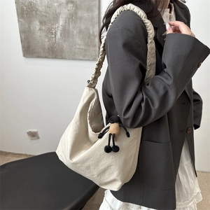 Minimalist cream drawstring pleated tote bag with plush pendant on casual grey blazer outfit