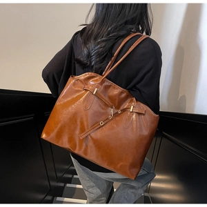Close-up of vintage brown tote bag with glossy leather and metallic buckle detail