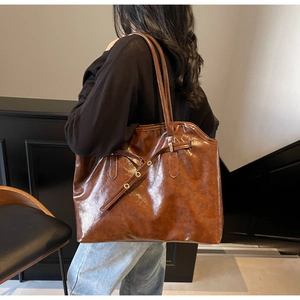 Detail of a large brown vintage tote bag in glossy PU leather with adjustable straps