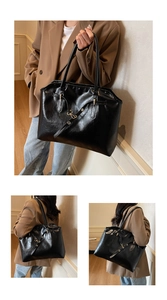 Detail view of a large black faux leather tote bag with metal buckles for women