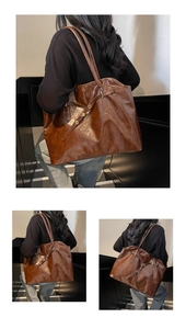 Detail of a large brown oil wax leather tote bag with minimalist shoulder straps and buckles