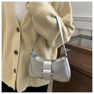 Close-up of matte silver baguette bag with metal buckle on model in chic indoor setting