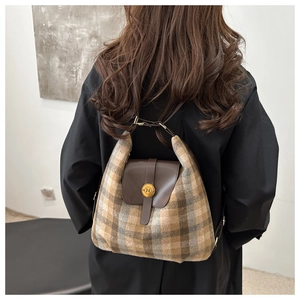Detail of wool plaid backpack with dark brown leather flap and golden N-letter buckle