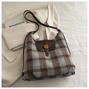 Detailed view of the plaid wool fabric texture and leather flap with gold N buckle