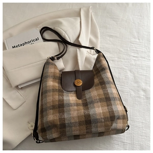 Close-up of retro plaid wool tote bag with brown leather flap and golden N-buckle detail
