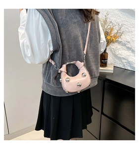 Close-up of pink crescent leather shoulder bag featuring large silver metal studs