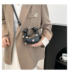 Close-up of a black crescent crossbody bag featuring decorative silver metal studs
