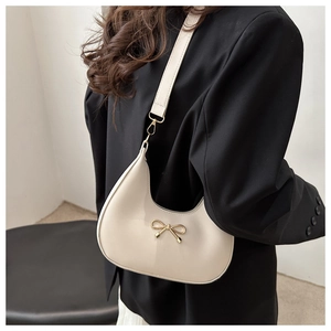 Detail of hobo bag with gold bow clasp on cream leather and wide shoulder strap