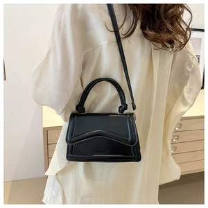 Detail of minimalist black crossbody bag with knotted handle and V-shaped stitching detail