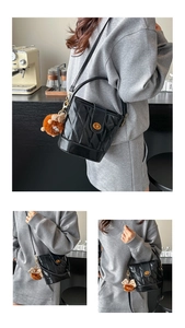 Détail d'un sac seau noir matelassé avec fermoir doré et charm de lion en peluche