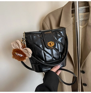 Détail du sac seau noir verni matelassé avec fermoir doré et breloque peluche