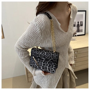 Close-up of leopard print shoulder bag with gold chain strap and metal bar detail