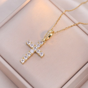 Détail macro du pendentif croix dorée avec zircons sertis sur une boîte en velours