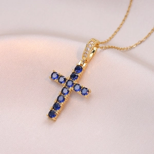 Collier élégant avec pendentif croix dorée et 11 zircons bleus sur fond de soie