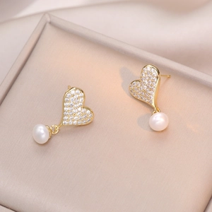 Orecchini a cuore d'oro con zirconi e perle d'acqua dolce su un vassoio per gioielli