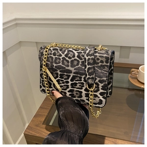 Detail of leopard print crossbody bag with gold chain strap in a cafe setting
