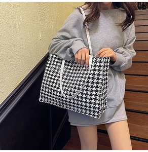 Detail of houndstooth tote bag on model showing large capacity and canvas shoulder straps