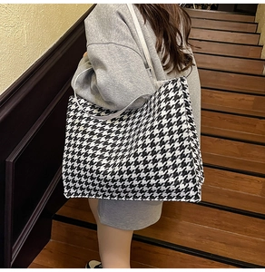 Detail of a large houndstooth tote bag shown on a model during a daily commute