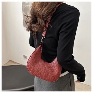 Detail of dark red woven hobo bag showing texture and golden metal hooks on shoulder