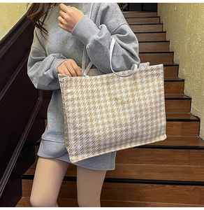 Detail of yellow houndstooth wool tote bag with white handles and textured canvas finish
