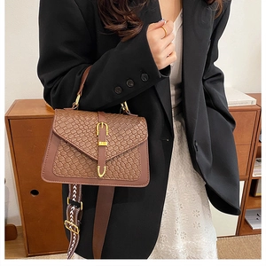 Detail of dark brown handbag with croc-embossed texture and ethnic style wide strap