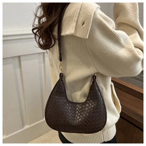 Detail of dark brown woven crescent underarm bag with gold metal link hardware