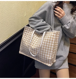 Side view of a large houndstooth tote bag in beige and white with slim shoulder straps