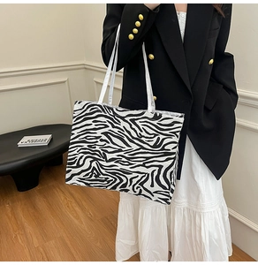 Detail of zebra pattern tote bag featuring durable fabric and slim white straps