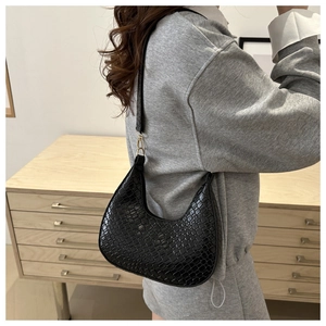 Detail of black crocodile texture on a crescent shoulder bag with gold hardware