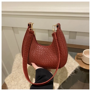Detail of brick red crescent bag showing woven leather texture and gold hardware