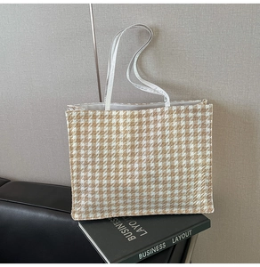 Detailed view of the houndstooth weave texture and leather handles on this tote bag