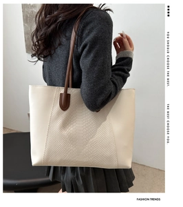 Detail of large tote bag in off-white leather with embossed snakeskin texture and brown handles
