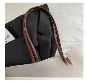 Close-up of beige crocodile pattern leather tote bag with dark brown stitched handles