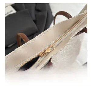 Detail of smooth gold zipper and woven texture on a minimalist tote bag