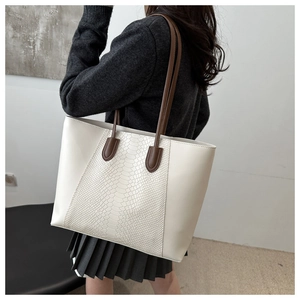 Detail of minimalist tote bag featuring snakeskin embossed texture and brown handles
