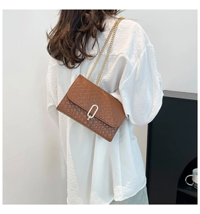 Detail of woven texture on brown PU leather crossbody bag with golden chain strap