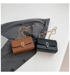 Detail of woven texture bags in brown and black with gold oval locks and chain straps