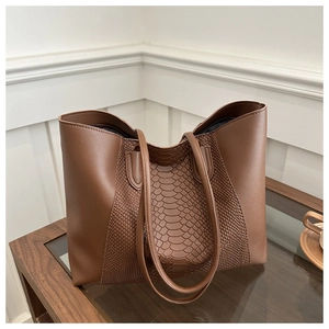 Detail of dark brown tote bag showing smooth and snake-embossed leather patchwork texture