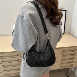 Stylish black woven leather crescent hobo bag with gold hardware worn by model