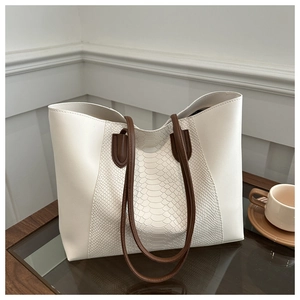 Detail of snake pattern texture on large white tote bag with deep brown handles