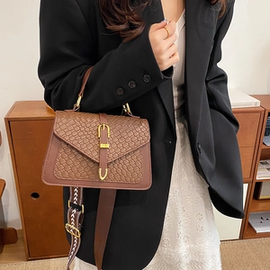 Brown contrast crossbody bag with crocodile texture and printed strap in a lifestyle setting