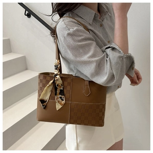Brown tote bag with checkered panel and silk scarf detail on handle in a lifestyle setting