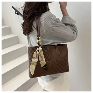 Detail of a brown patchwork tote bag with checkered texture and decorative scarf