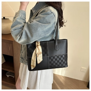 Close-up of black leather tote bag with checkerboard pattern and elegant silk scarf