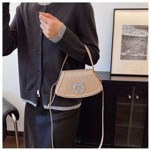 Sac de soirée chic doré champagne avec boucle en cristal porté avec une tenue moderne