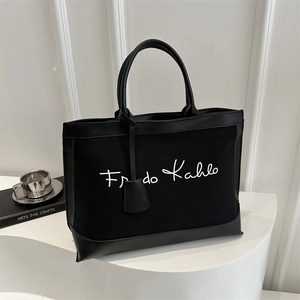 Close-up of black canvas tote bag with Frida Kahlo embroidery and leather trim