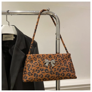 Close-up of leopard print shoulder bag with silver metallic bow detail and faux suede texture
