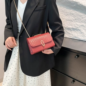 Chic red woven crossbody bag with gold U-buckle shown on a stylish model outfit