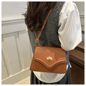Detail of dark brown retro crossbody bag with golden round swivel lock and fine stitching