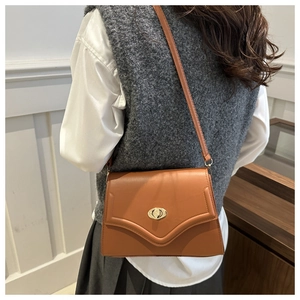 Detailed back view of a caramel brown crossbody bag with gold oval twist lock and slim strap